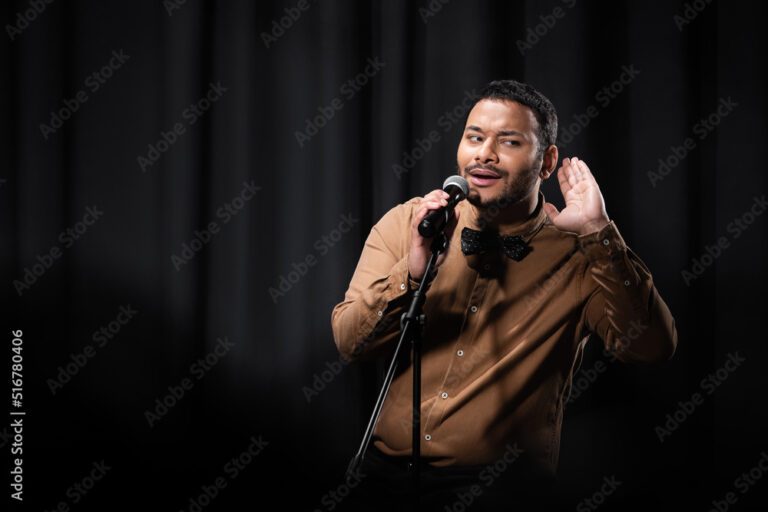 indian comedian listening during stand up comedy show on black.